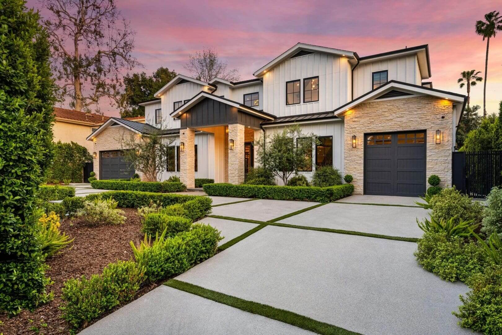 Modern house with landscaped driveway at sunset.