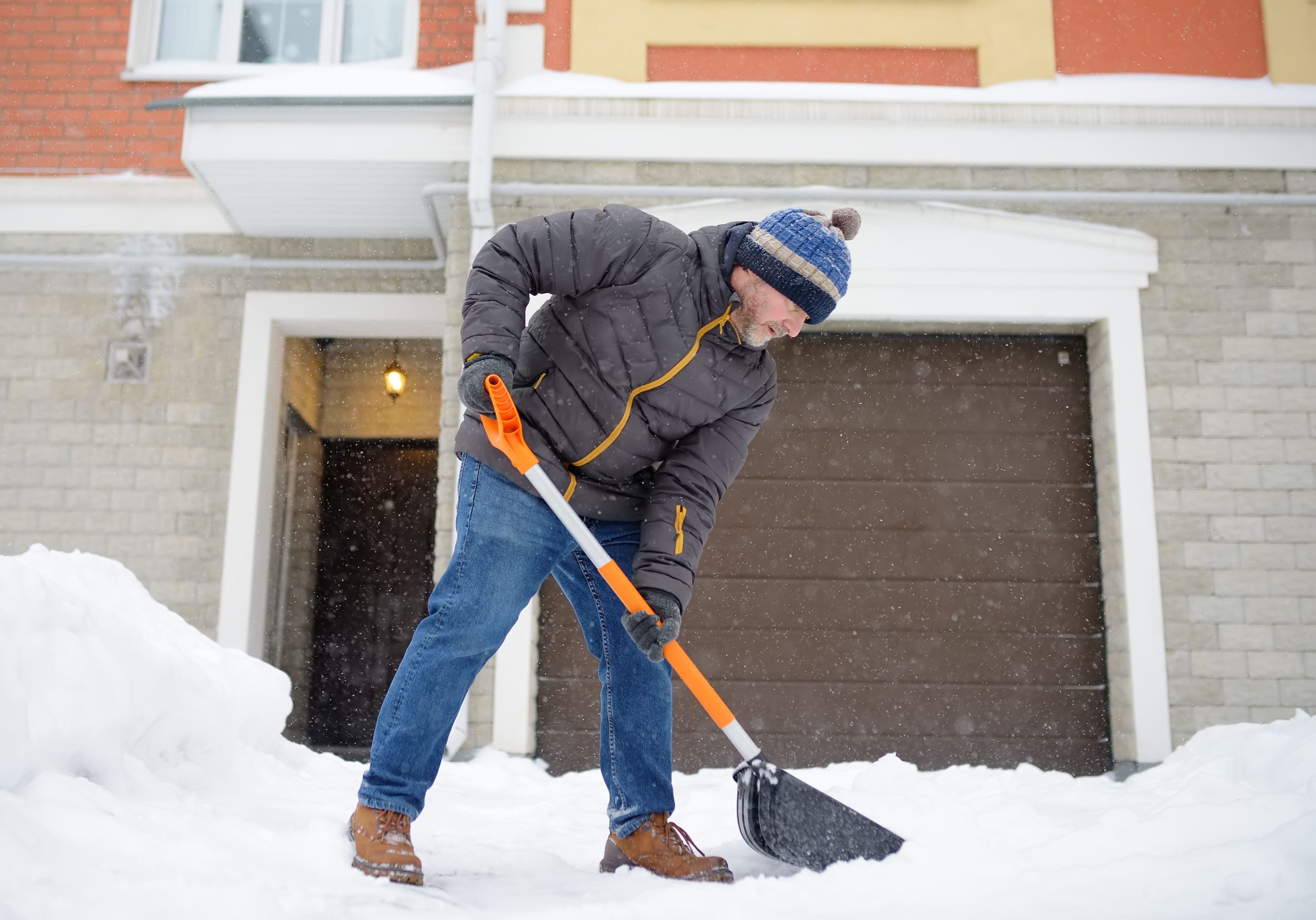 Person shoveling snow in front of house.