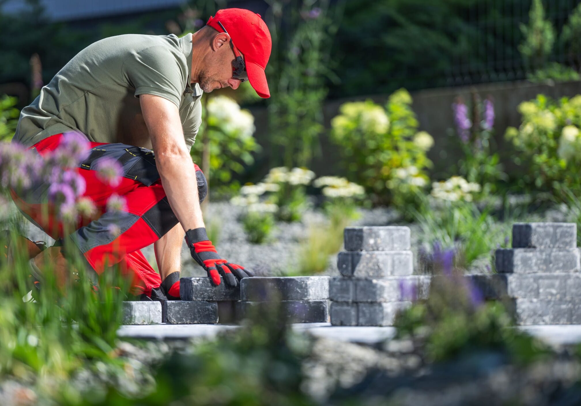 Man arranging stone blocks in garden.