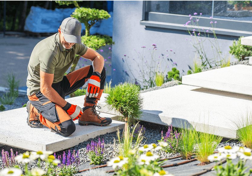 Gardener kneeling on stone steps, tending plants.